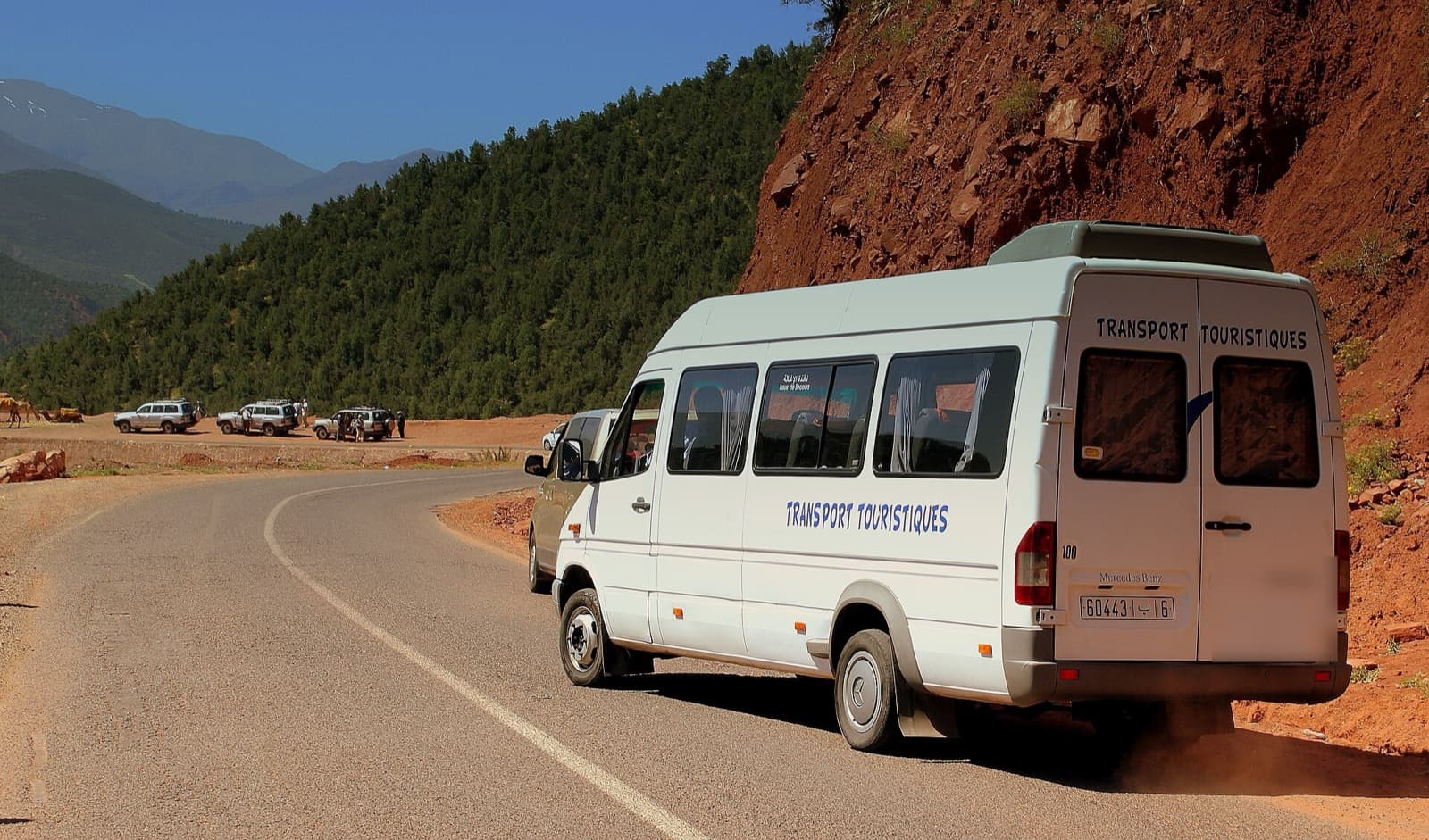 A white tourist minibus on a mountain road in the High Atlas